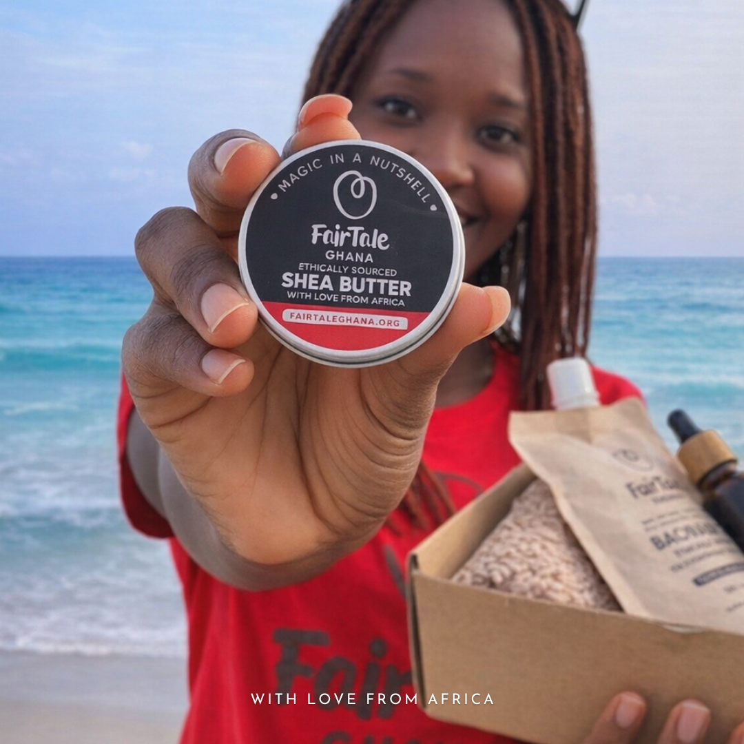A woman at the beach holding a FairTale GHANA Shea butter tin, gift box open beside her